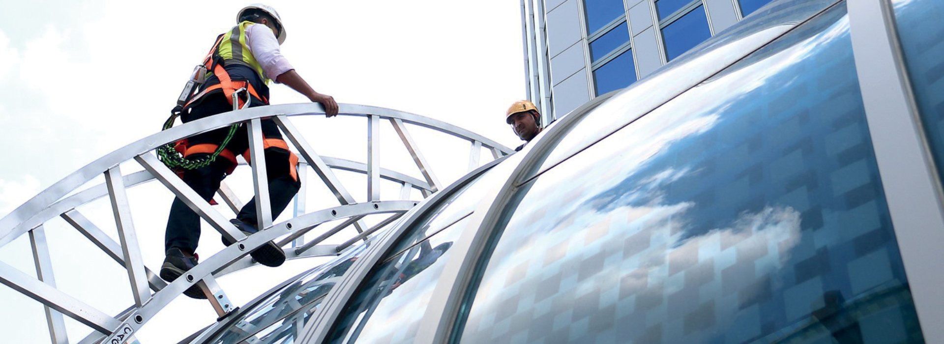 Tekniker arbetar på höjd med aluminiumstege vid service av byggnad
